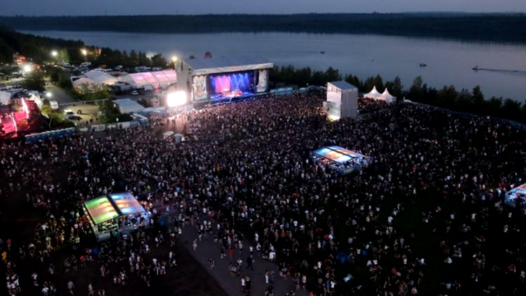 Festivalgäste tanzen vor buntem Bühnenlicht.