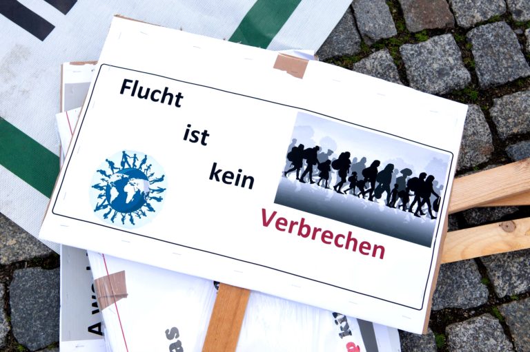 Menschen protestieren für Asylsuchendenrechte.